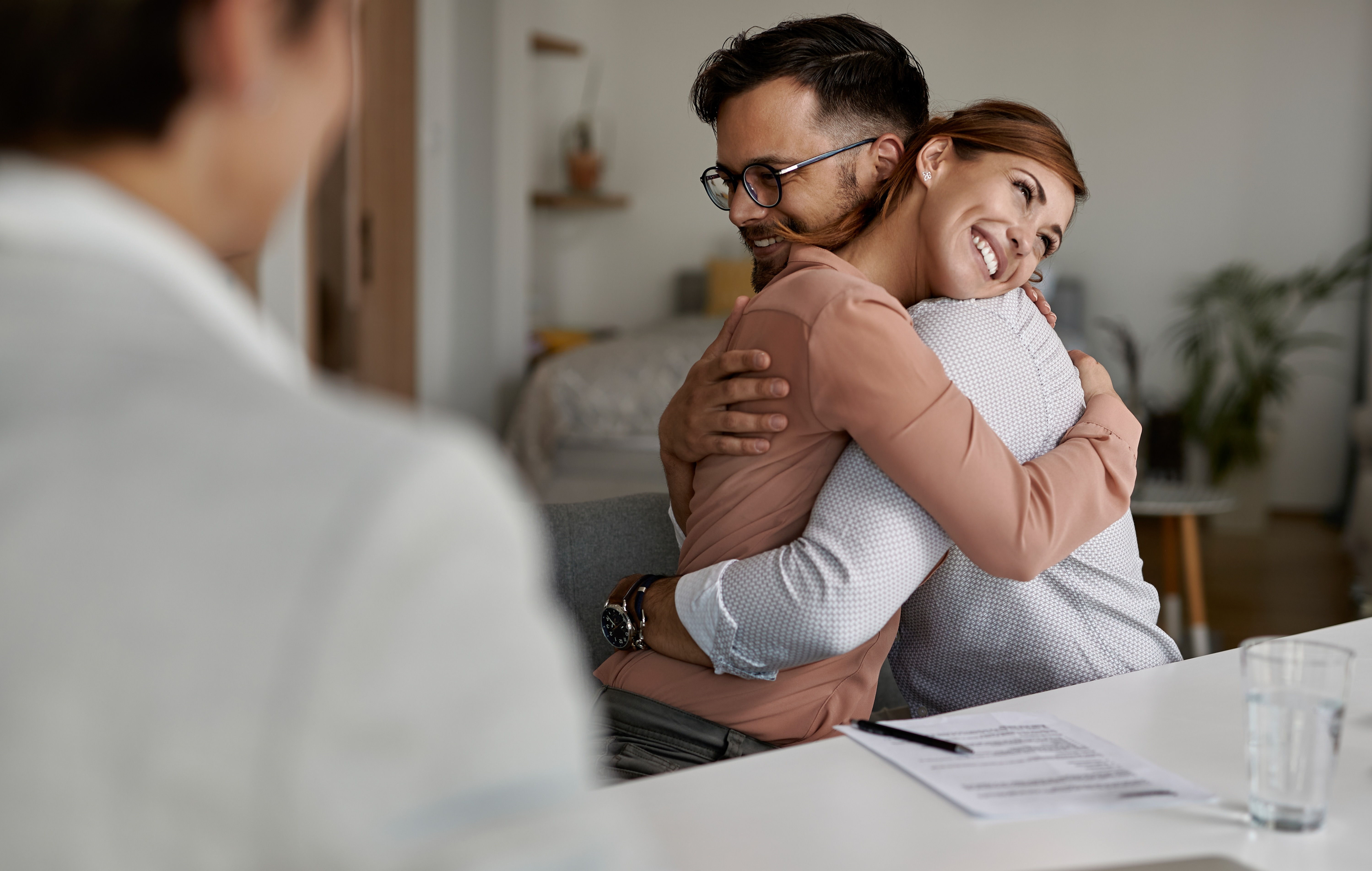Young happy couple embracing after successful meeting with their real estate agent.